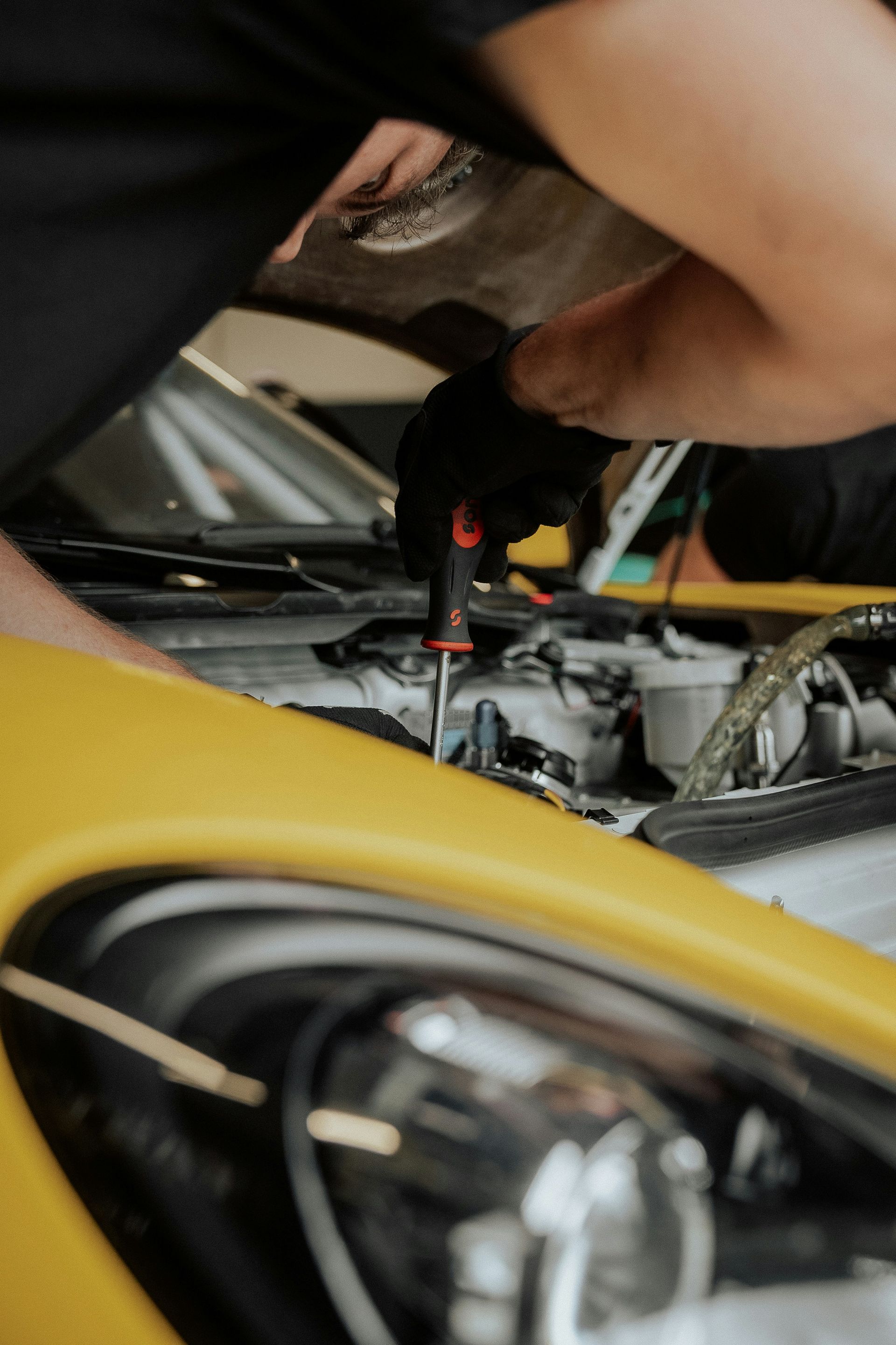 A mechanic is working on a yellow car.